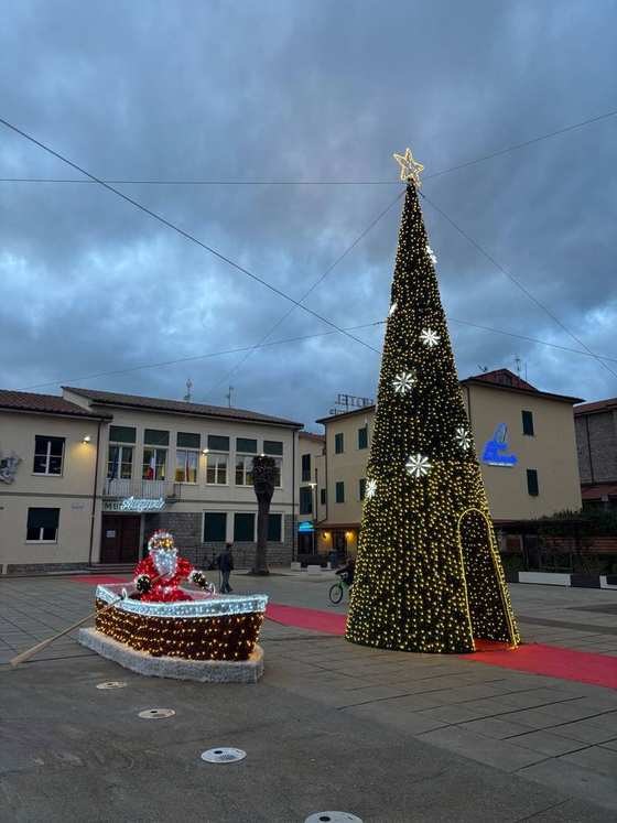Un albero di Natale luminoso e un Babbo Natale su una barca in piazza