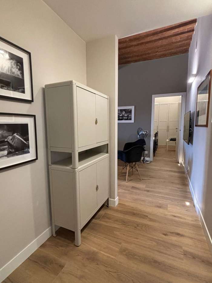 Corridoio con parquet, soffitto in cotto e legno originale, quadri in bianco e nero e, in fondo, il soggiorno