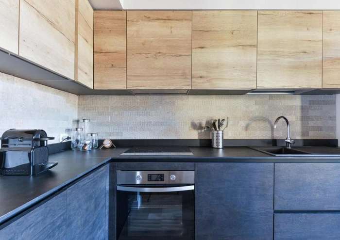 Cucina con ante in legno chiaro, piano scuro, forno e piano cottura