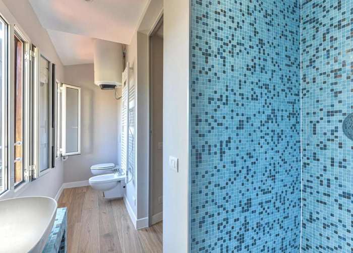 Doccia rivestita di mosaico azzurro e bagno con finestre