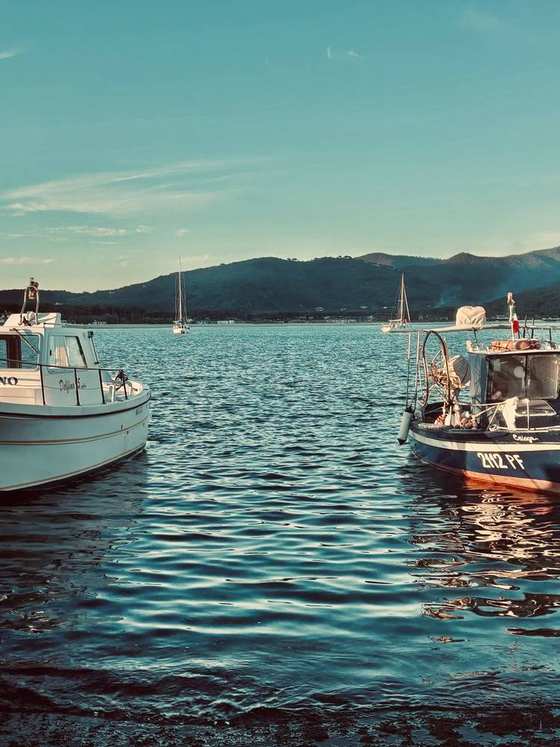 Due barche ormeggiate nel porto, con le colline sullo sfondo al tramonto