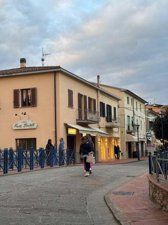 Una strada del centro al tramonto, con i negozi illuminati