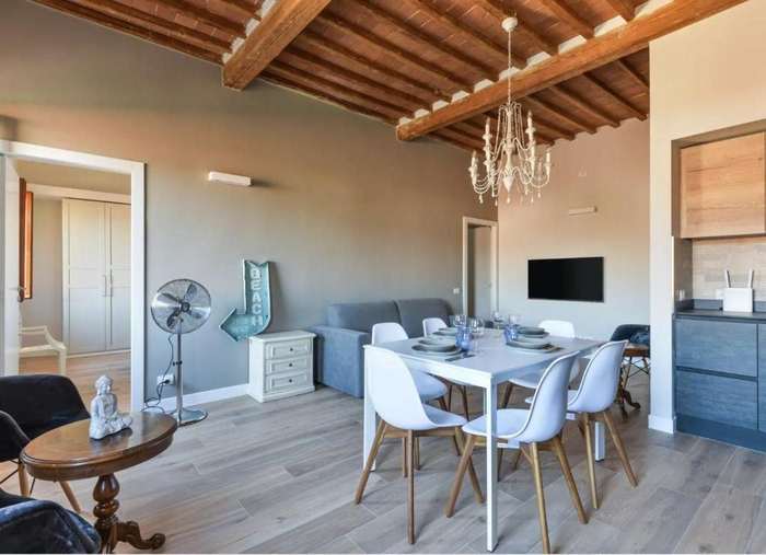 Tavolo da pranzo apparecchiato sotto il lampadario, con il soffitto in legno