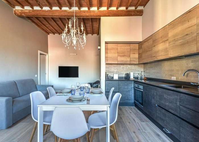 Zona giorno con lampadario, tavolo, divano e cucina a vista